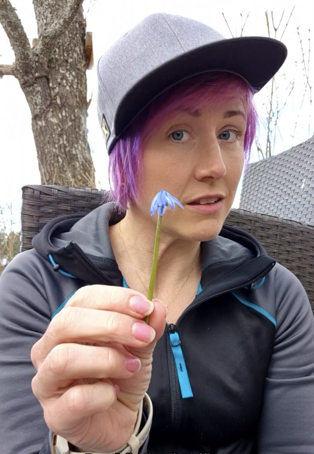 Barnmorskan håller en hel blomma i handen och tittar mot kameran.